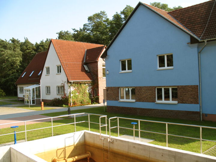 Wasserwerk Beeskow: Hauptgebäude links und Wasserwerksgebäude rechts, im Vordergrund ein Abflussbecken